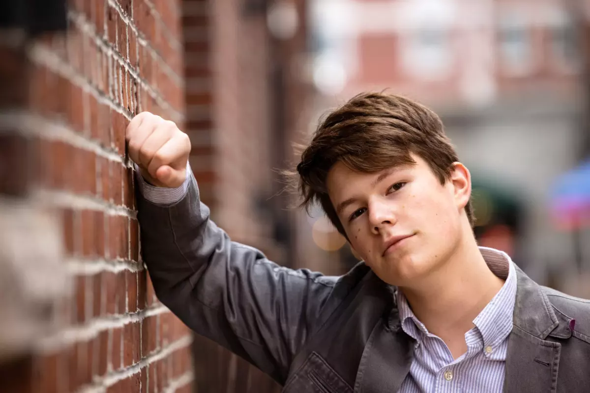 maine high school student photographed in portland maine with blazer against brick wall for senior pictures