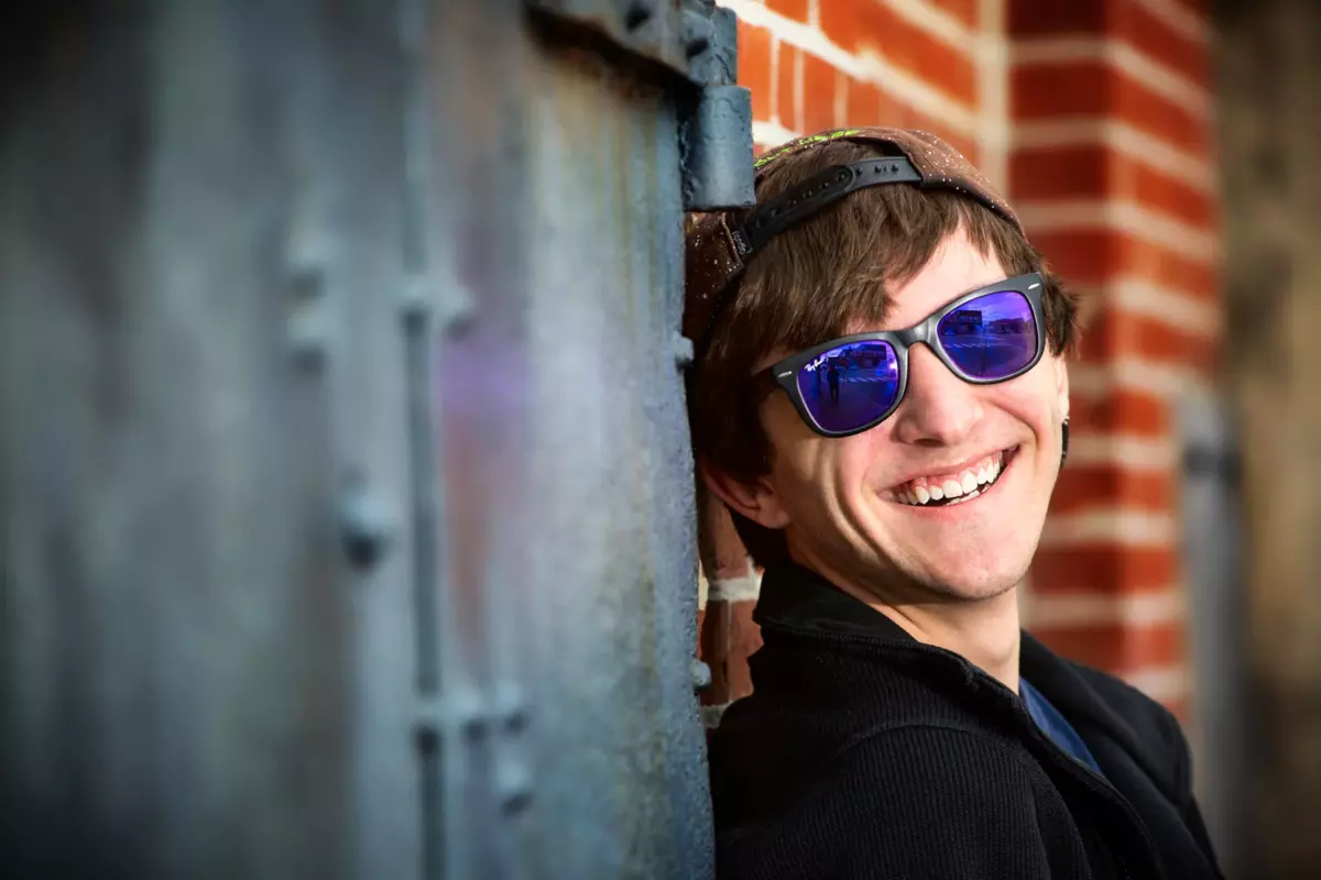 maine senior boy photographed with sun glasses against brick wall in portland, maine