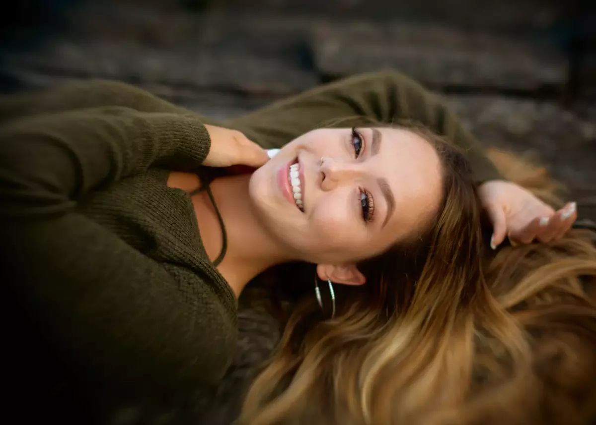 pretty high school girl photographed laying down on rocks with flowing hair for senior pictures