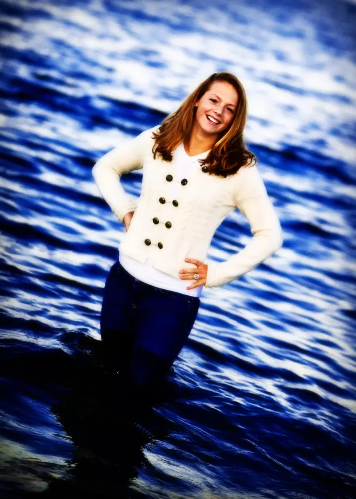 professional senior photos in maine at the beach for girl in sweater standing in the ocean