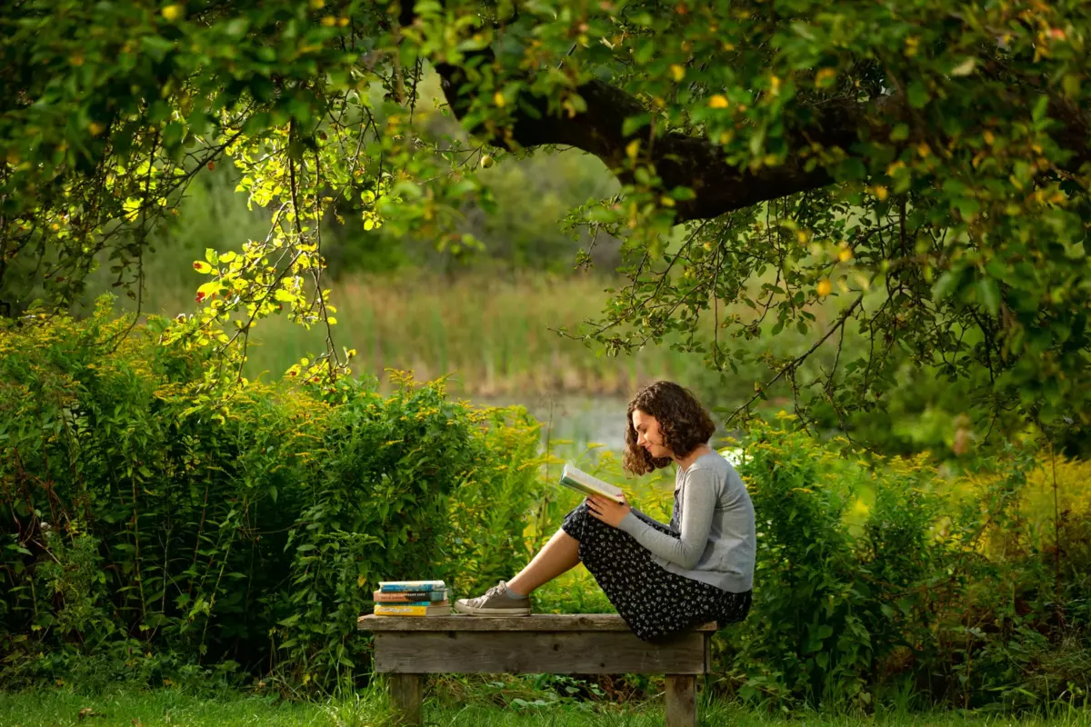 scarborough high school senior pictures at nature center in falmouth maine of girl reading a textbook under apple tree