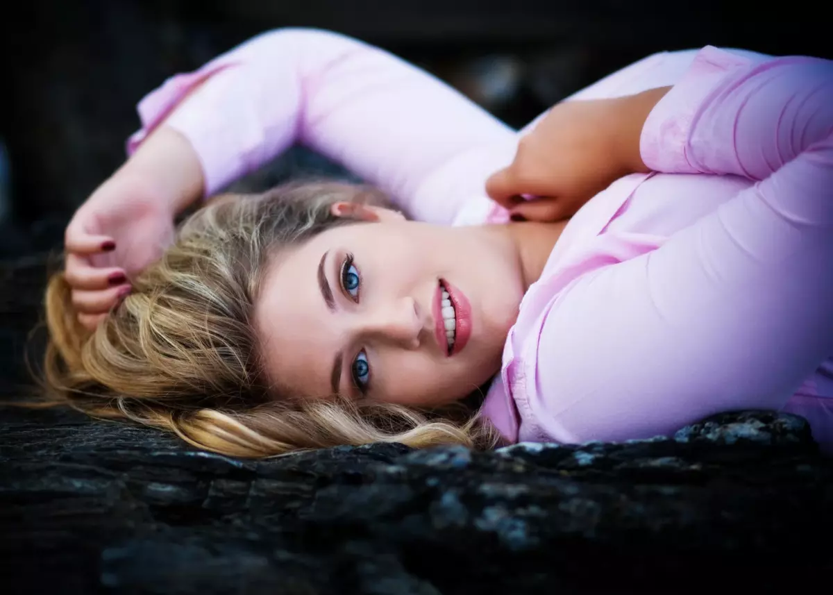 senior girl in pink shirt laying on rocks at beach in maine senior portrait photoshoot