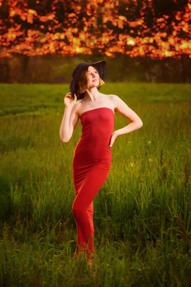 senior girl photographed at nature preserve with red dress and hat in falmouth, maine