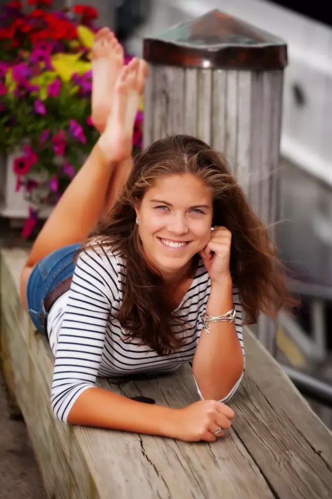 senior picture of girl in striped top lying on dock wood hardware at nautical photo shoot in portland maine