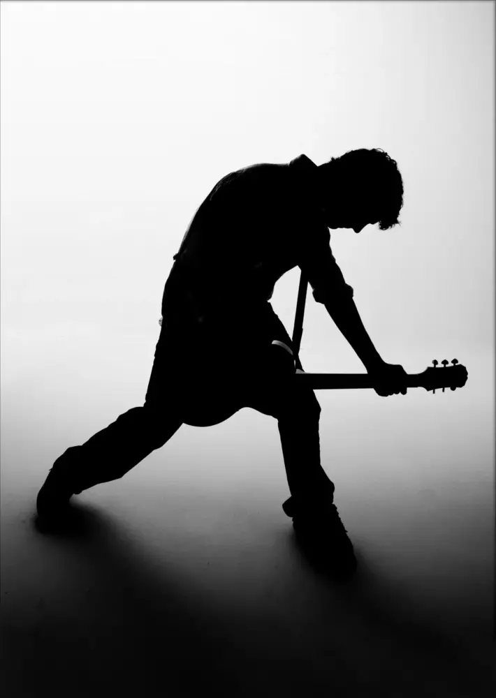 senior picture of high school boy with guitar in backlit silhouette