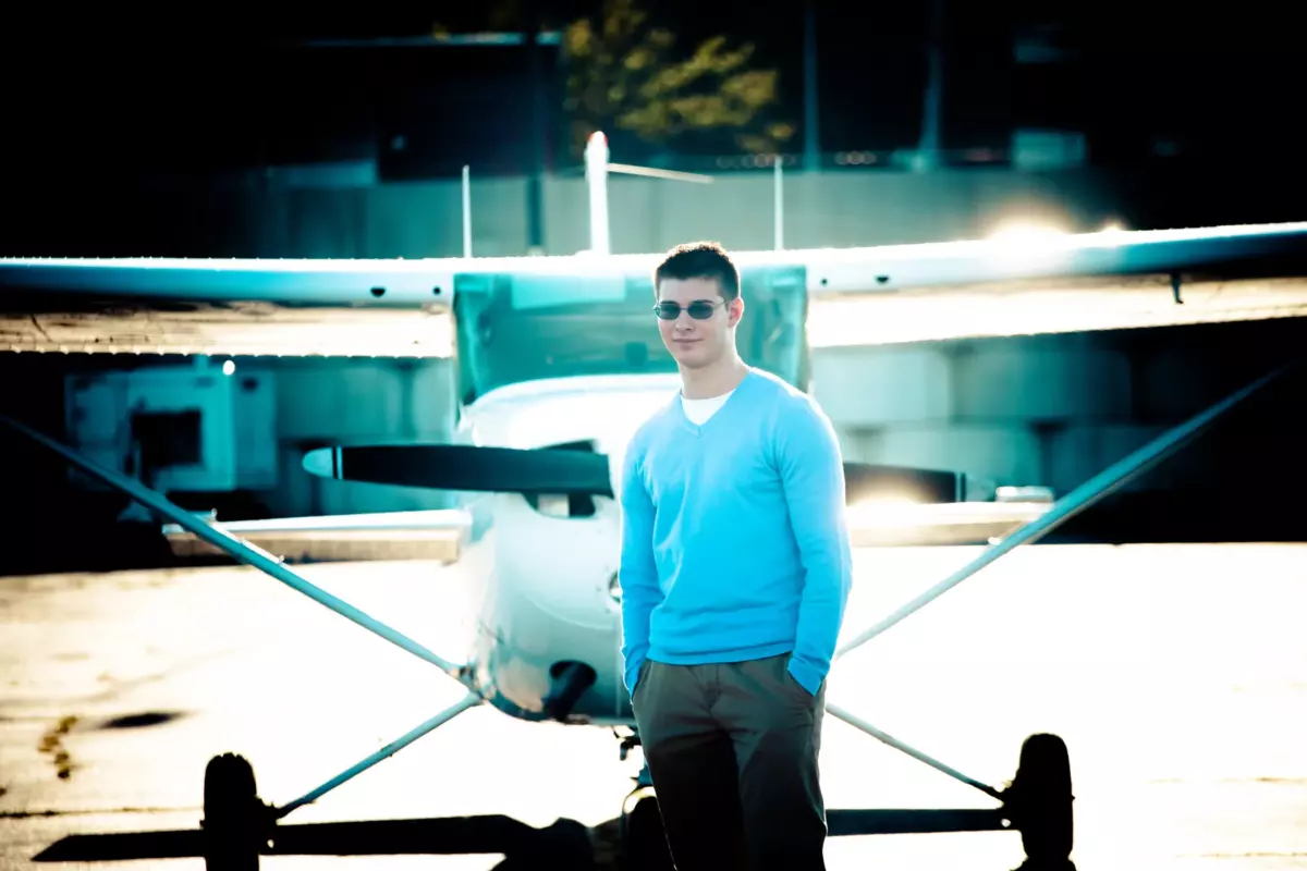 south portland high school senior boy photographed at jetport/airport with plane on runway for senior picture