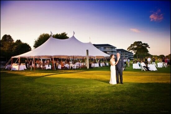 Outdoor Maine wedding reception with white tent, couple embracing, sunset backdrop, elegant decor. Perfect for Wedding photography by Maine photographer. 