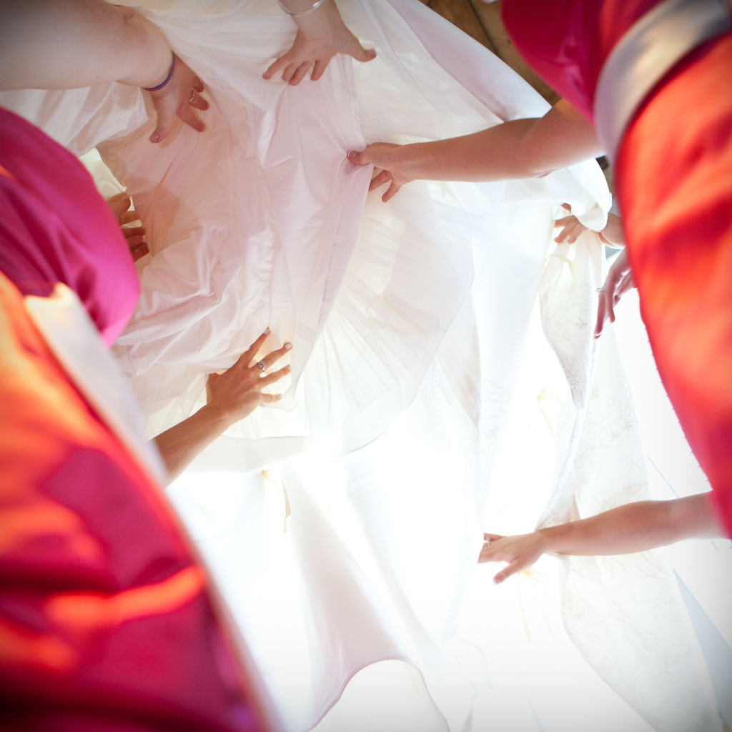 Bridesmaids hold a wedding dress above their heads at Samoset resort wedding in rockport, maine.