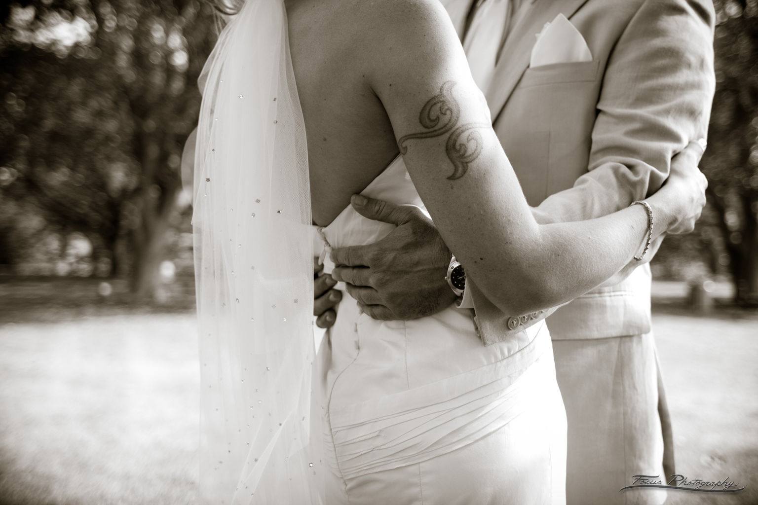Groom embracing bride with tattoo