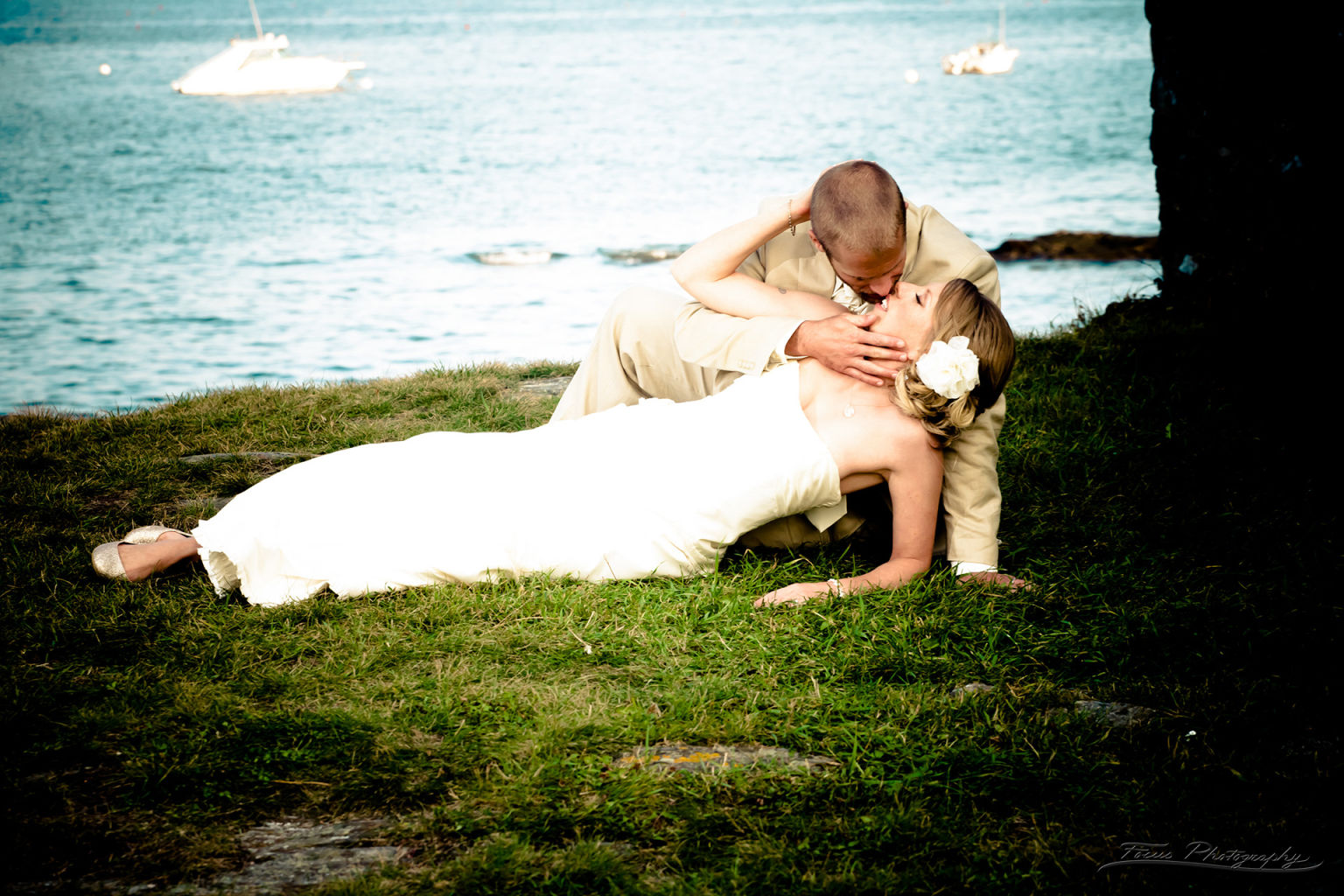 Bride lying down kissing groom at Maine beach