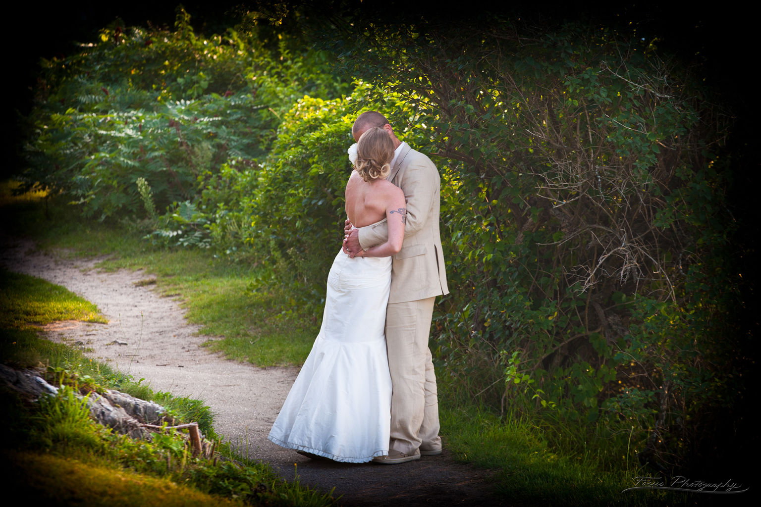 Bride and groom kissing on path in Maine