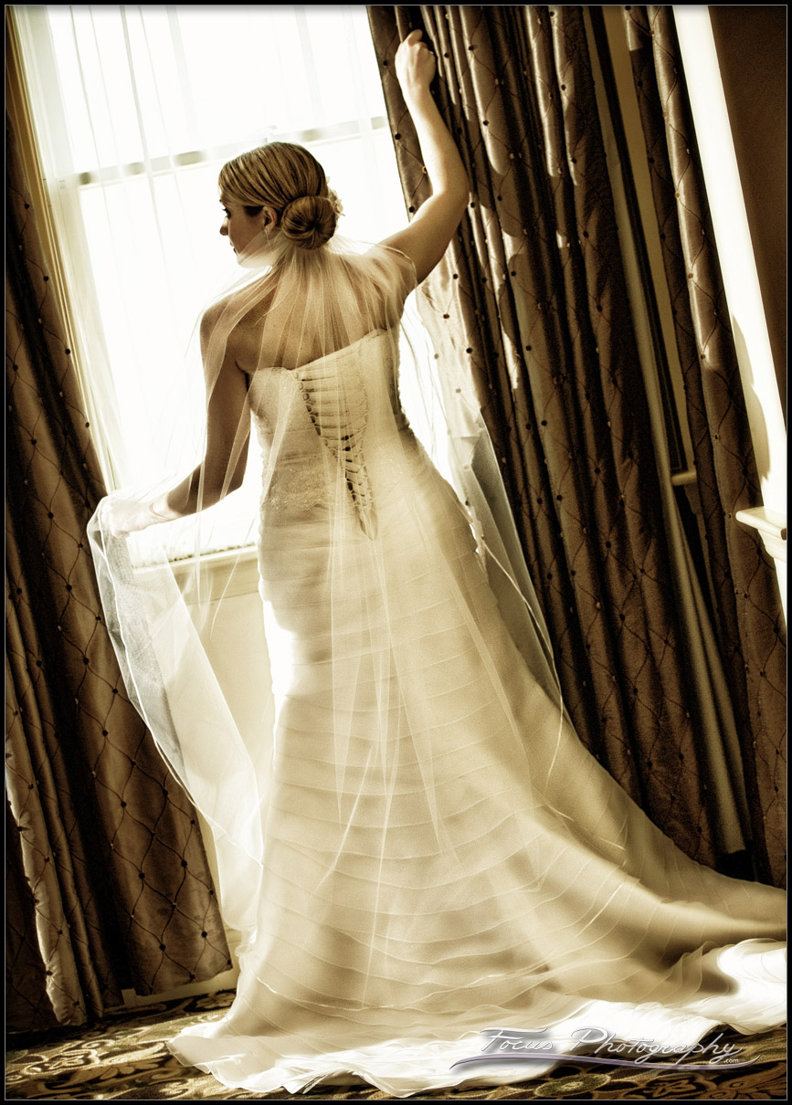 The wedding gown from the back, as the bride looks out the window