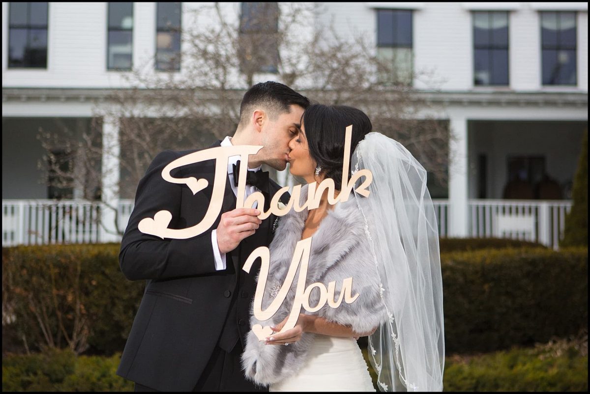 couple kisses behind thank you sign