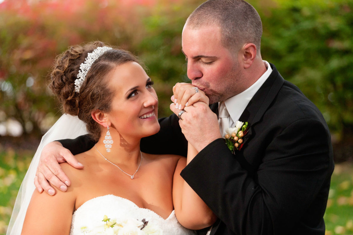 Red Barn Wedding, groom kisses bride's hand