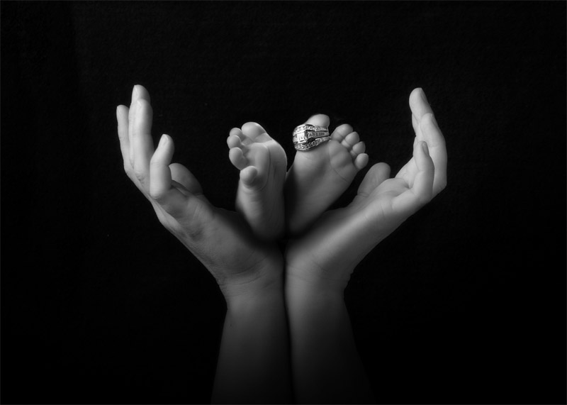mother's hands holding baby feet with ring on them