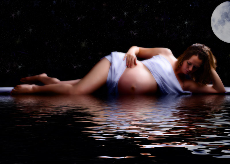 maternity picture created in pregnancy photo studio of woman laying on ground with moon and stars overhead