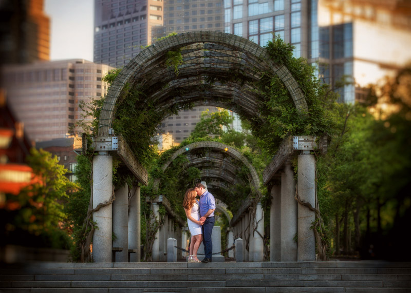 Engagement photo of couple taken in Boston with city behind them