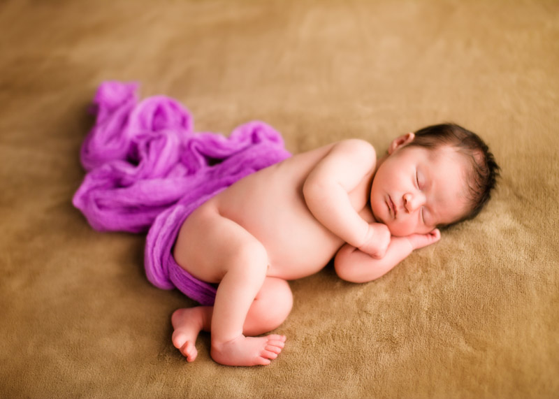 newborn baby picture taken in studio of baby girl with purple scarf
