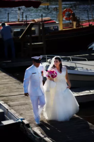 Bride and groom in military attire walk on dock near boats wedding ceremony - Nonantum resort in Kennebunkport