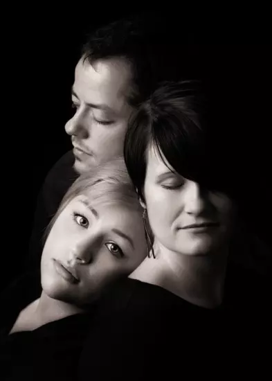 Portrait of three individuals embracing with eyes closed in a serene posture; perfect for wedding photography and family portraits. 